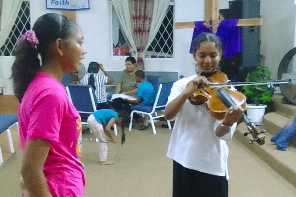 Two kids learning to play violin.